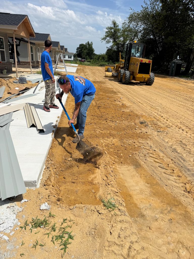 Black Water crew hand-grading soil along a curb on a residential site development project